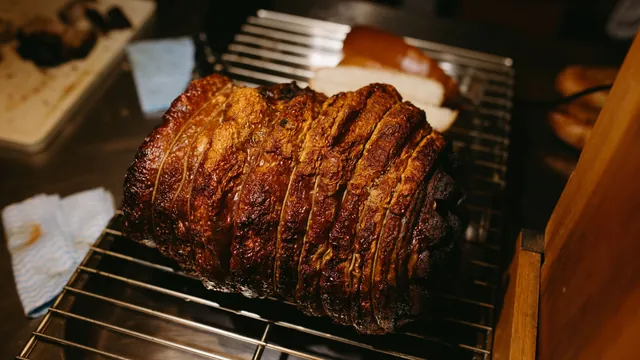 A slow-roasted pork roast with crisp, crackling skin resting on a wire rack
